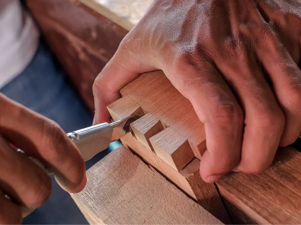 hands carving dovetail joint joinery in wood